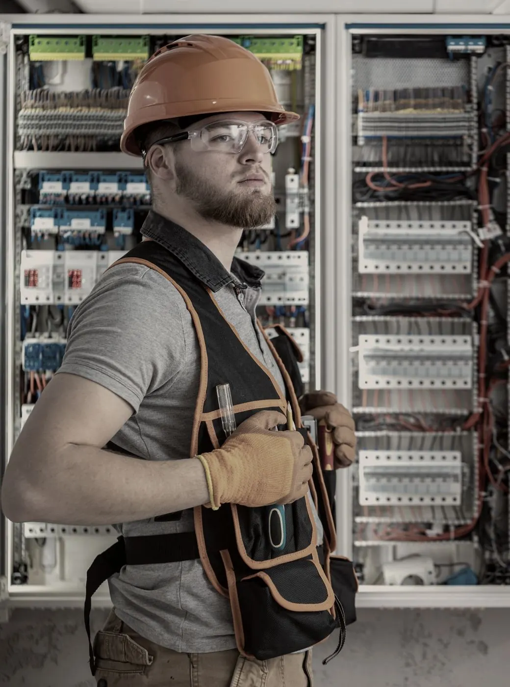 Elektricien in werkkledij voor een schakelkast