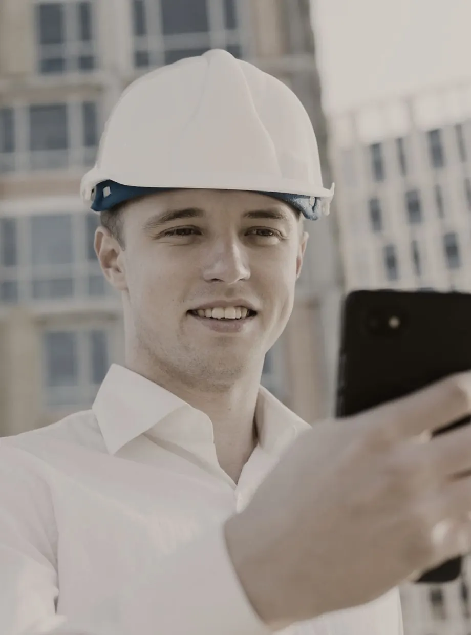 Vakman met helm kijkt naar zijn smartphone